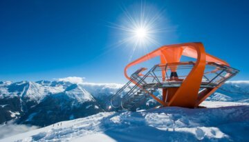 Orange Aussichtsplattform in verschneiter Berglandschaft unter blauem Himmel. | © Gasteiner Bergbahnen AG