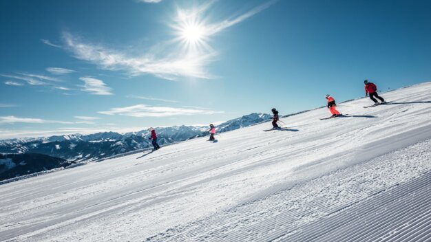 Group of skiers on a groomed slope on a sunny day. | © Zell am See-Kaprun Tourismus