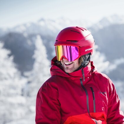 Skier wearing a red helmet and goggles in the snow. | © ATOMIC
