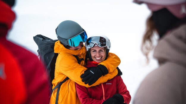 Skiers hugging in the snow. | © ATOMIC