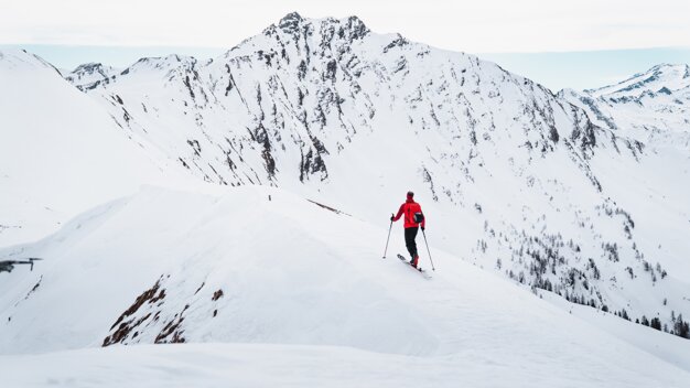 Skier in red jacket on snow-covered mountain | © ATOMIC