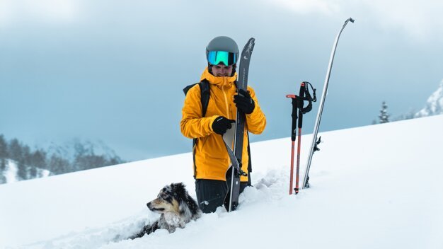 Skier with dog in the snow | © ATOMIC