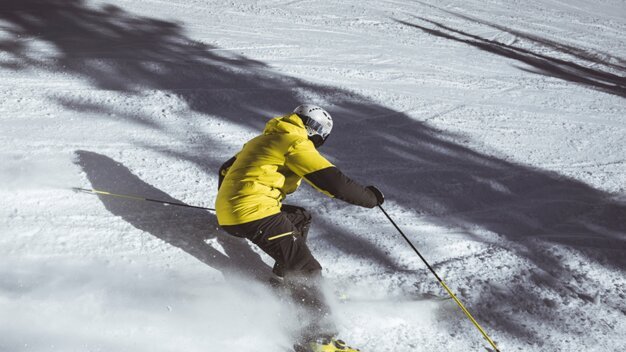 Skier in a yellow jacket skiing in the snow. | © Patrick Bätz
