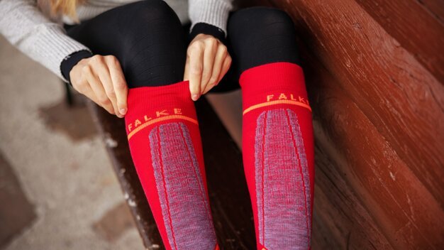 Person putting on red FALKE knee socks. | © FALKE