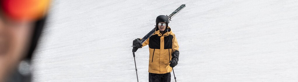 Skier carrying skis on shoulder walking on snow. | © www.robybragotto.com
