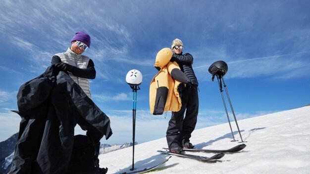 Two skiers on a snowy mountain with ski equipment. | © Oakley