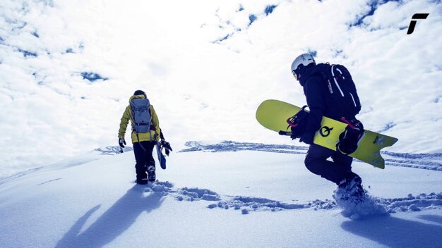 Zwei Snowboarder wandern durch den Schnee. | © Reusch