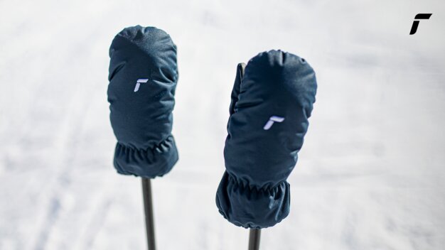 Two navy blue mittens with white logo on ski poles in snow. | © Reusch