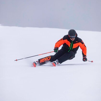 Skier in orange and black jacket skiing down a slope. | © Rossignol / Louis Garnier