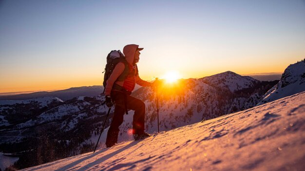 Hiker with backpack in snow at sunrise. | © Salomon