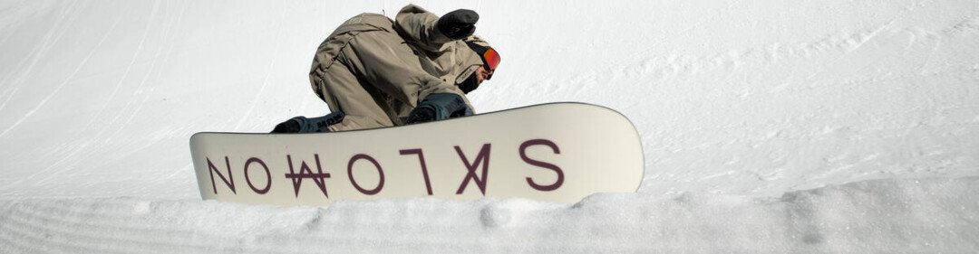 Snowboarder kneeling on a Salomon snowboard in the snow. | © SALOMON