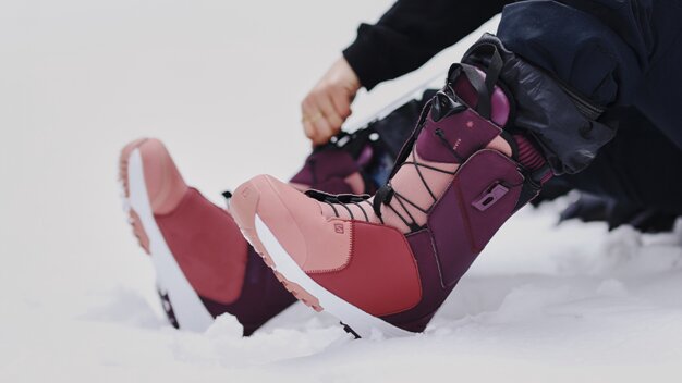 A pair of purple and pink snowboard boots in the snow. | © SALOMON