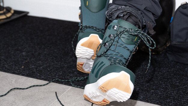Green snowboard boots with white and tan soles. | © SALOMON