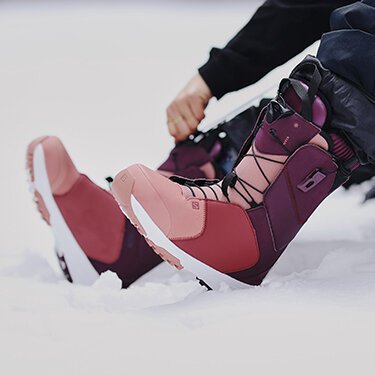 Burgundy colored snowboard boots in the snow. | © SALOMON