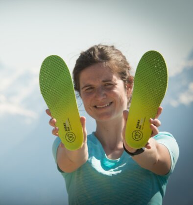 Woman holding up green shoe insoles. | © Au fil des Lumières