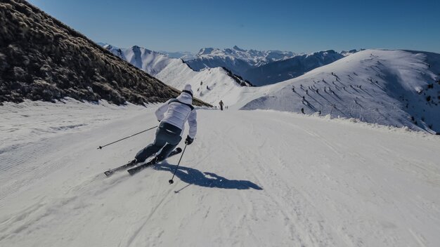 Skifahrer auf schneebedeckter Piste mit Bergpanorama | © Thermic / Loic Schutz