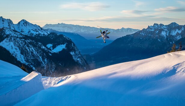 Skier performing a jump in front of a mountain range. | © VÖLKL / c.Pally-Learmond