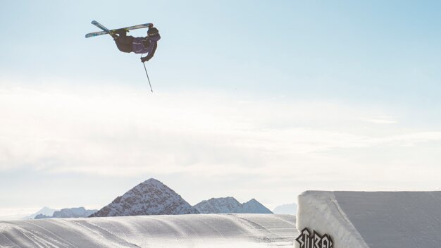 Skier performing a jump off a ramp with mountain backdrop. | © VÖLKL / Syo van Vliet