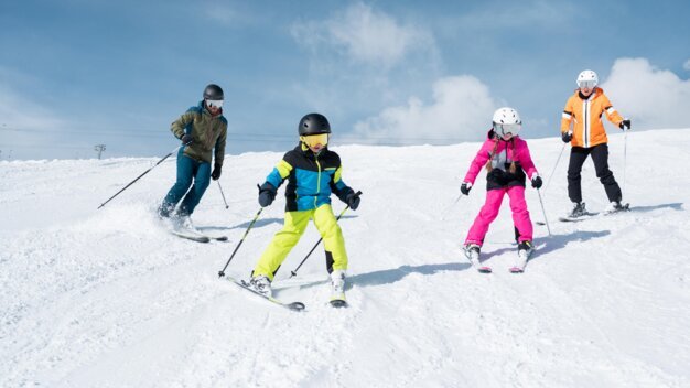 A family skiing down a snow-covered slope. | © McKINLEY