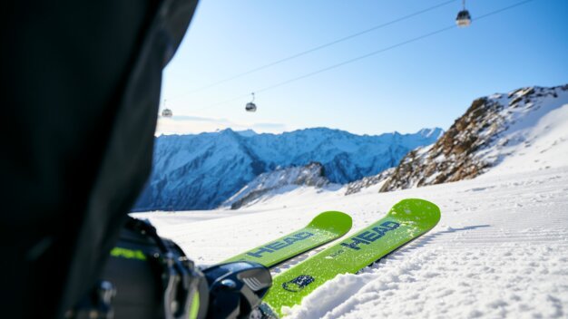 Green skis in snow with mountain view