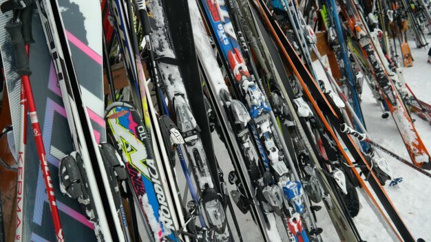A collection of skis and ski poles leaning against a wall.