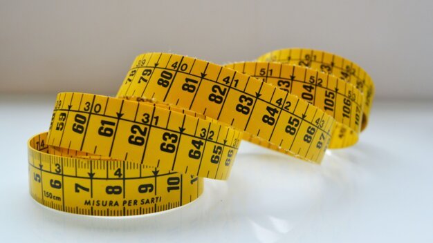 Gelbes Maßband auf einer glänzenden Oberfläche