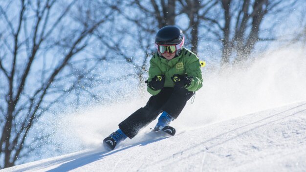 Kind fährt Ski auf einer schneebedeckten Piste.