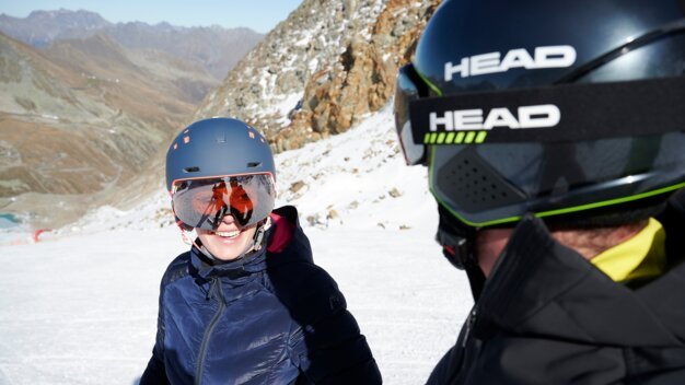 Two skiers on a ski slope, one smiling.