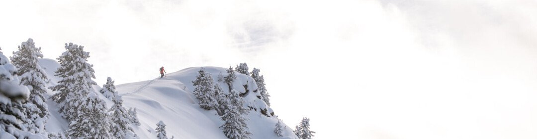 Snowy mountainside with a person at the summit. | © Tim Marcour