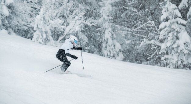 Skifahrer bei Schneefall auf schneebedeckter Piste. | © Tim Marcour