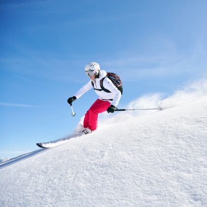 Skifahrerin fährt einen schneebedeckten Hang hinunter.