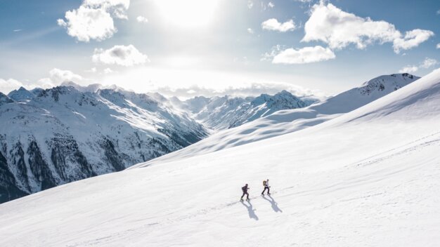 Zwei Personen beim Skitourengehen in verschneiter Berglandschaft