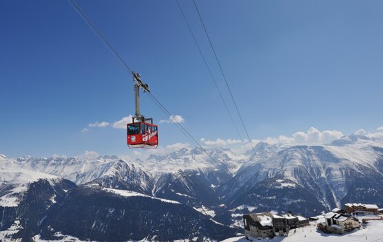 Red cable car in front of snow-capped mountains. | © aletscharena.ch / PERRET