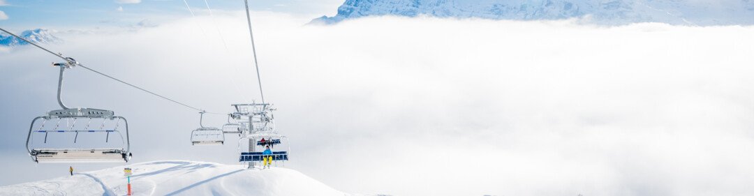 Télésiège au-dessus d'une pente enneigée avec fond de montagne | © Niels Ebel / Région Dents du Midi
