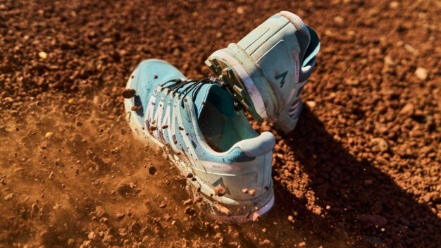 Zwei blaue Sportschuhe auf braunem Untergrund mit aufgewirbeltem Staub.