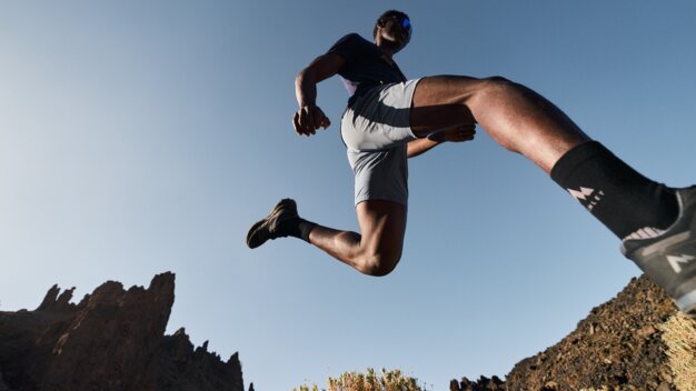 Mann springt in bergiger Landschaft