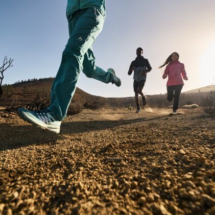 Trois personnes courant sur un sentier poussiéreux.