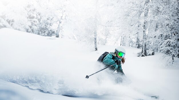 Skier carving through deep powder in a snowy forest. | © Atomic Austria GmbH