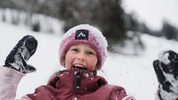 Laughing girl in snow with hat and gloves. | © INTERSPORT International Corporation GmbH