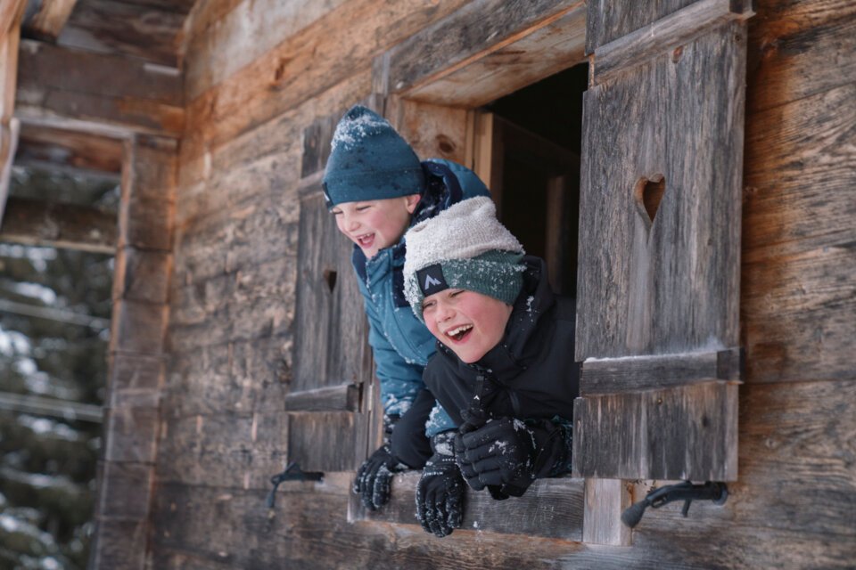 Zwei lachende Jungen schauen aus einem Fenster mit Herz-förmigem Ausschnitt. | © INTERSPORT International Corporation GmbH
