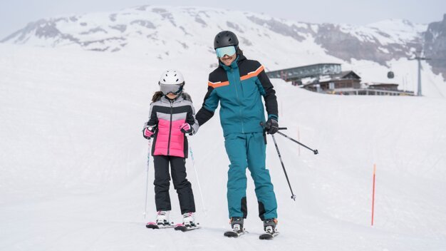 Père aidant sa fille à skier. | © IIC/McKINLEY