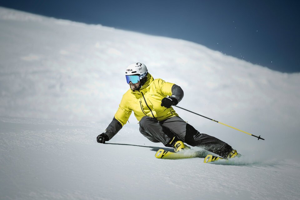 Skifahrer in gelber Jacke fährt eine schneebedeckte Piste hinunter. | © Fischer Sports GmbH
