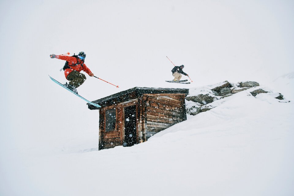 Two skiers jumping over a building in the snow. | © Fischer Sports GmbH