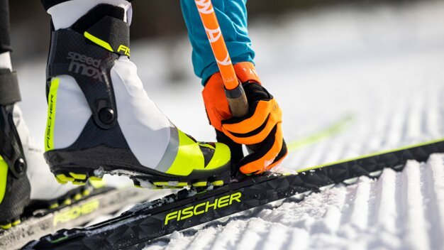 Cross-country ski boot on ski with orange gloves. | © Fischer Sports GmbH