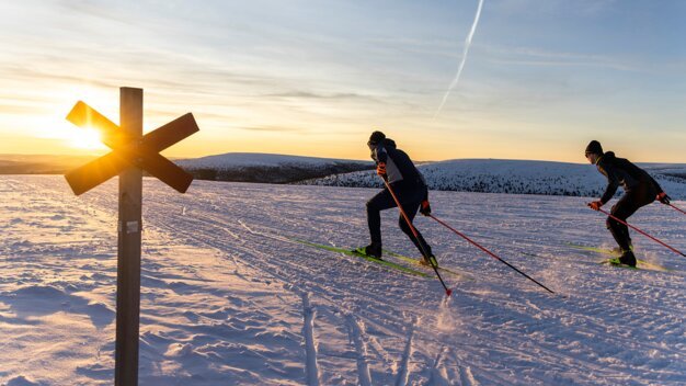 Two cross-country skiers in a snowy landscape at sunset. | © Fischer Sports GmbH