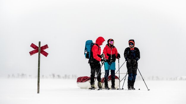 Gruppe von Skifahrern mit Schlitten im Schneesturm an einem Wegweiser. | © Fischer Sports GmbH