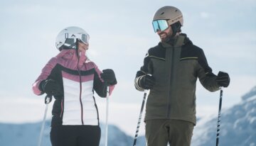 Zwei Skifahrer in Skikleidung stehen lächelnd im Schnee. | © INTERSPORT International Corporation GmbH