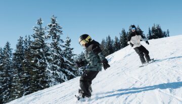 Zwei Snowboarder auf einer schneebedeckten Piste