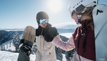 Two snowboarders shaking hands in the snow. | © INTERSPORT International Corporation GmbH