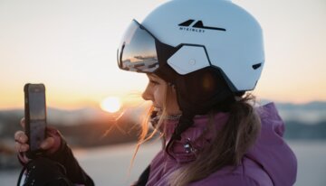 Woman with ski helmet filming sunrise with phone | © INTERSPORT International Corporation GmbH
